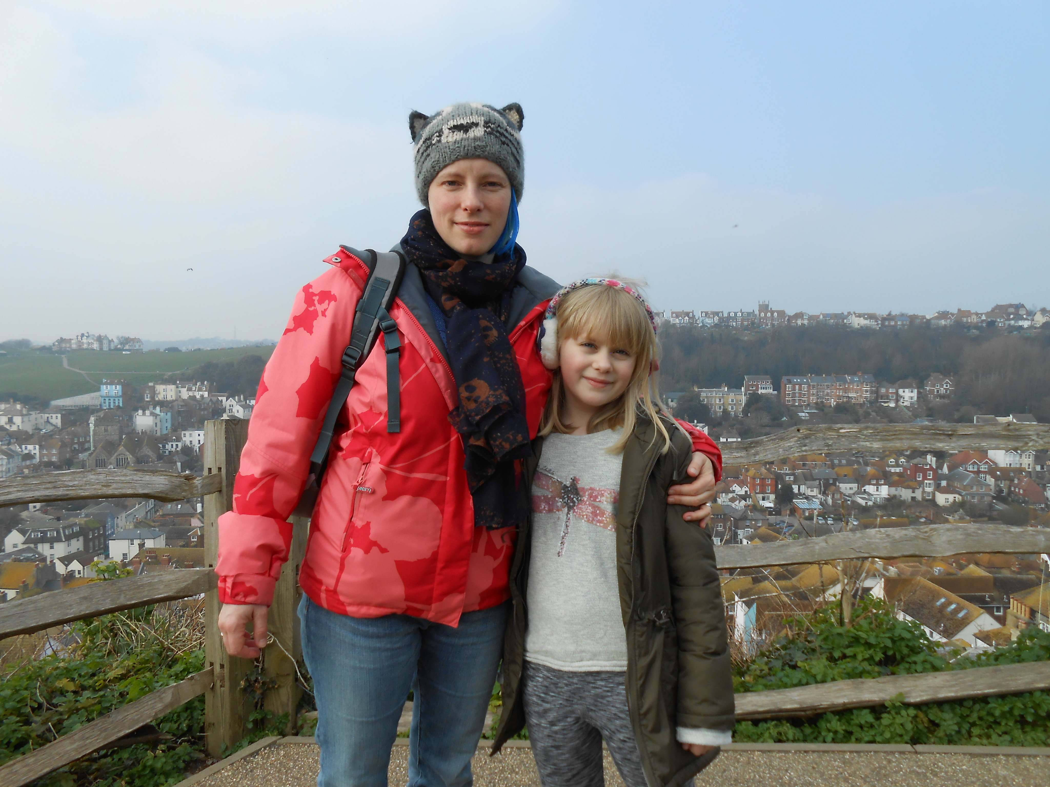Diny with a child at an outdoor viewpoint overlooking a town